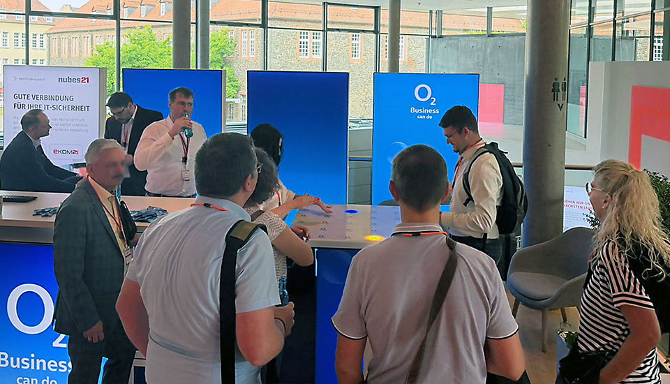 Besucherinnen und Besucher im Gespräch am gemeinsamen Stand von o2 Business und ekom21 auf der eXPO26.