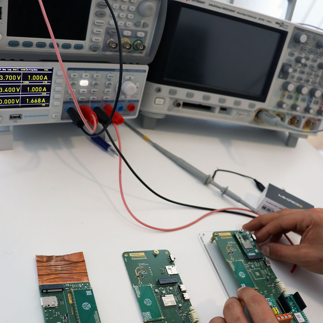 Messplatz mit Oszilloskop und Labornetzteil, davor mehrere IoT-Leiterplatten mit integrierten Antennen