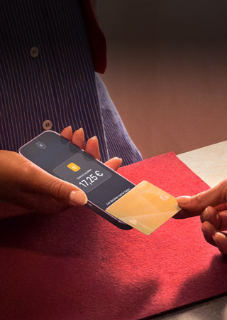 Eine Hand hält eine Kreditkarte an ein iPhone, um eine Transaktion abzuschließen