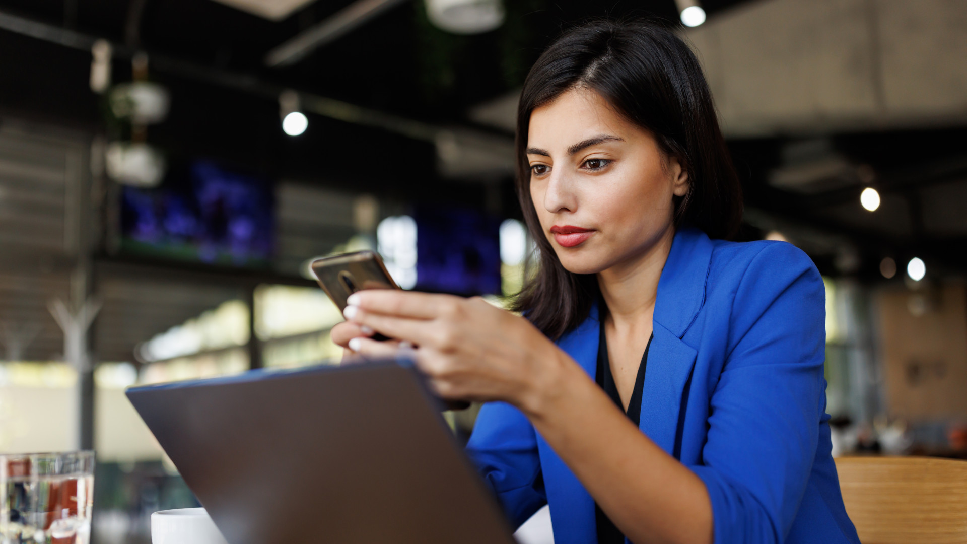 Moderne Geschäftsfrau mit Handy und Laptop bei der Arbeit