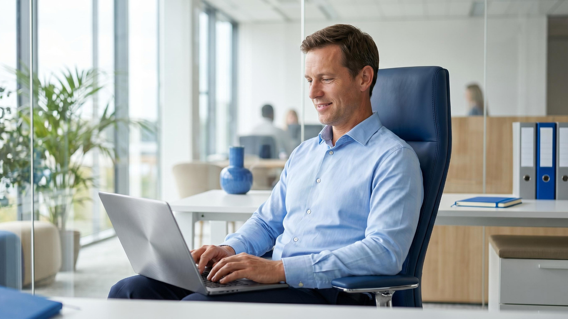 Eine Person sitzt im Büro und nutzt einen Laptop.