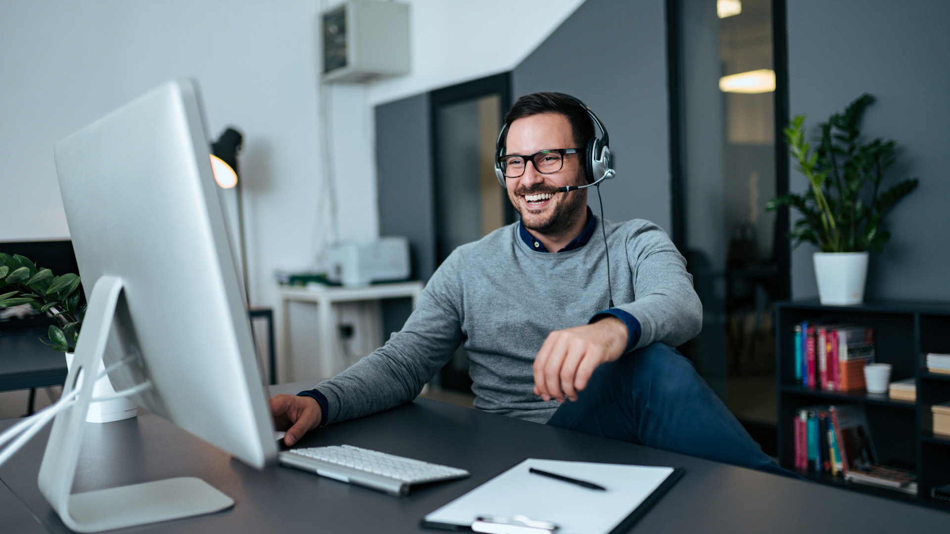 Ein junger Mann mit Headset telefoniert im Büro über Teams 