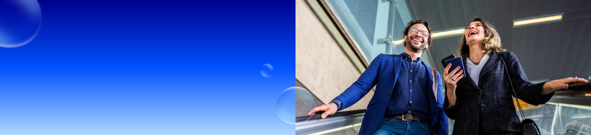 Abbildung: Eine Frau mit einem Smartphone in der Hand und ein Mann gehen lachend eine Treppe herunter.