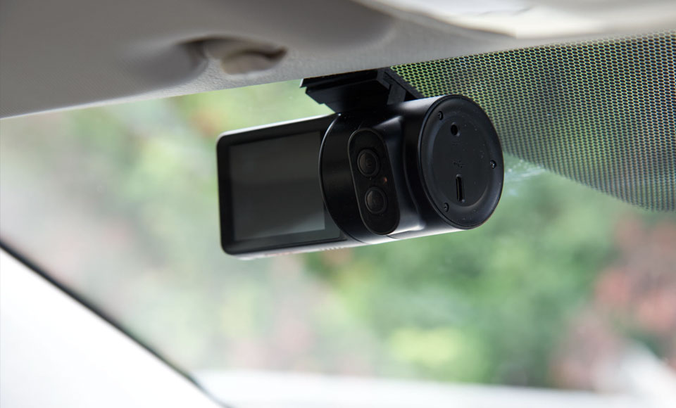 Innenaufnahme eines Fahrzeugs mit montierter Dashcam an der Frontscheibe, Blick auf Kameraeinheit und Halterung.