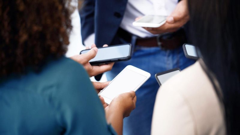 Mehrere Personen stehen zusammen und halten Smartphones in den Händen, die Bildschirme sind sichtbar.